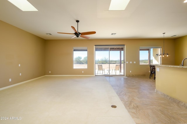 spare room featuring baseboards, a ceiling fan, visible vents, and a skylight