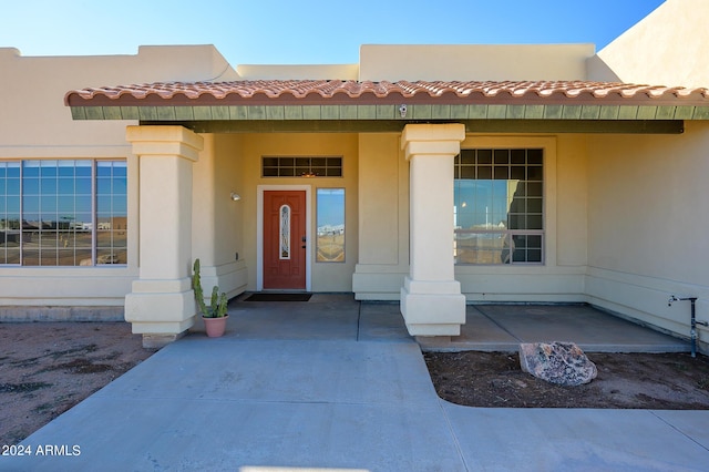 property entrance with stucco siding and a tiled roof