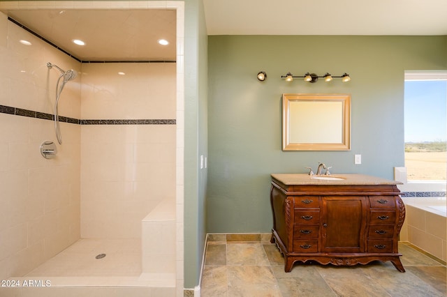 full bath featuring a tile shower, vanity, a bathtub, stone finish floor, and baseboards