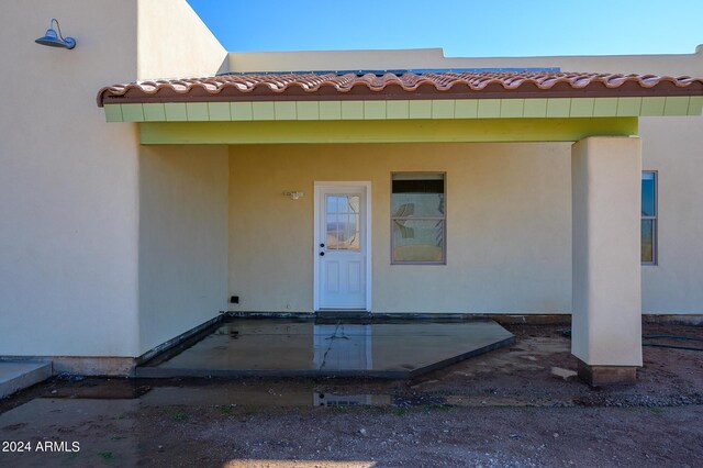 entrance to property with a tile roof and stucco siding