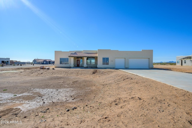 pueblo revival-style home featuring concrete driveway, an attached garage, and stucco siding
