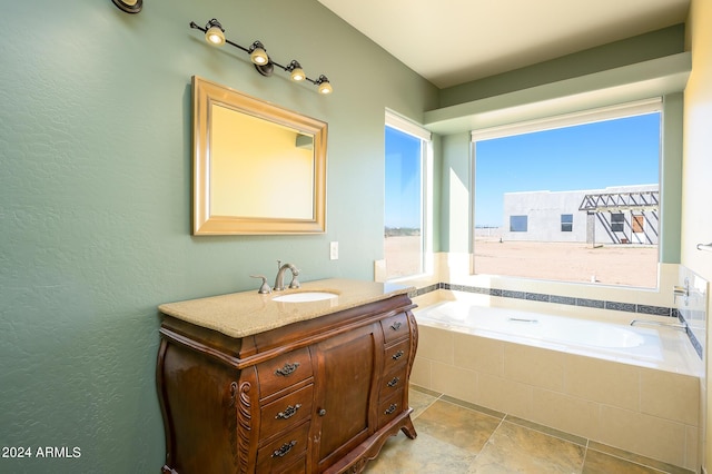 bathroom with vanity, stone finish flooring, a textured wall, and a bath