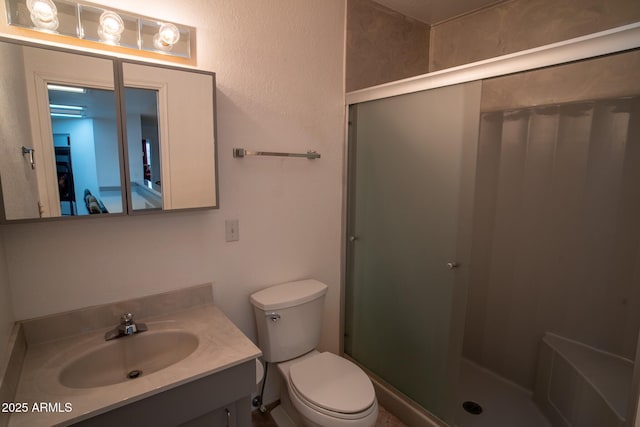 bathroom featuring vanity, a shower with shower door, and toilet