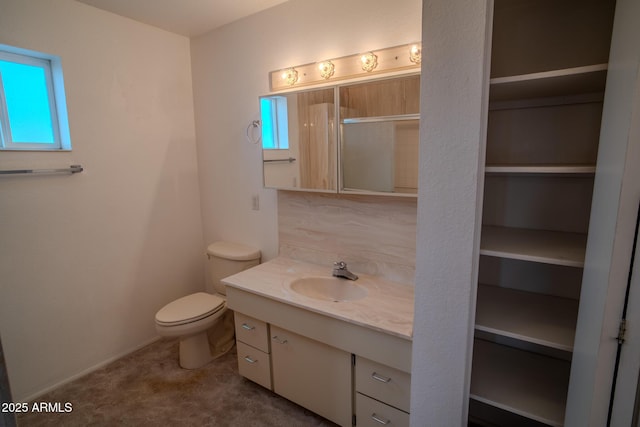 bathroom featuring vanity, toilet, and backsplash