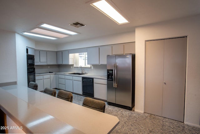 kitchen featuring a kitchen bar, kitchen peninsula, sink, and black appliances