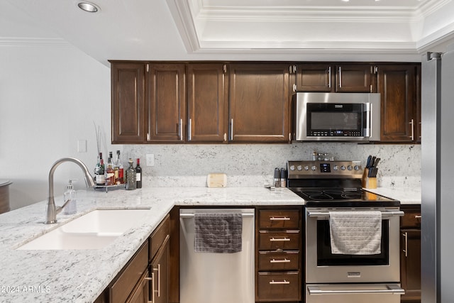 kitchen with appliances with stainless steel finishes, sink, decorative backsplash, dark brown cabinetry, and crown molding