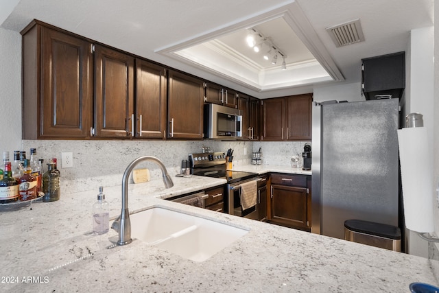 kitchen featuring sink, appliances with stainless steel finishes, backsplash, ornamental molding, and a raised ceiling