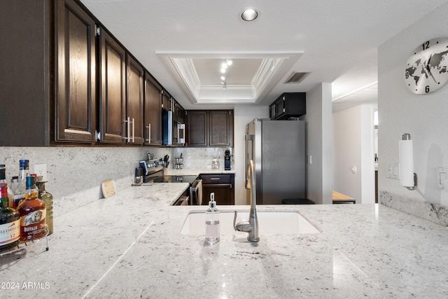 kitchen with appliances with stainless steel finishes, backsplash, a tray ceiling, crown molding, and dark brown cabinets