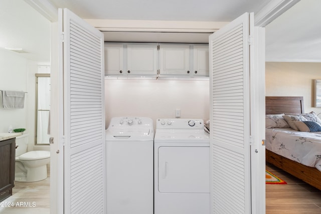 laundry area featuring separate washer and dryer, light hardwood / wood-style flooring, and ornamental molding