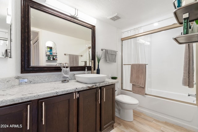 full bathroom featuring enclosed tub / shower combo, vanity, wood-type flooring, a textured ceiling, and toilet