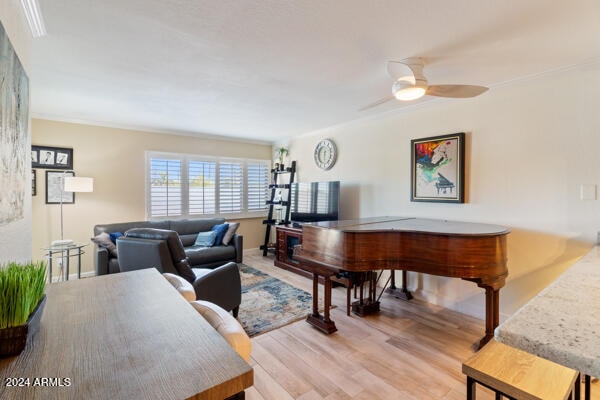 living room with crown molding, light hardwood / wood-style floors, and ceiling fan