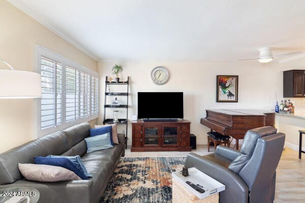 living room with crown molding, ceiling fan, and light wood-type flooring