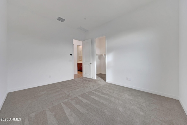 unfurnished bedroom with light carpet, a closet, and a walk in closet