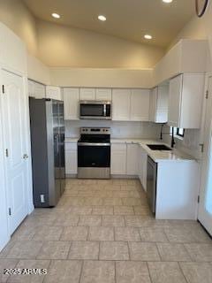 kitchen featuring appliances with stainless steel finishes, a sink, light countertops, white cabinetry, and recessed lighting