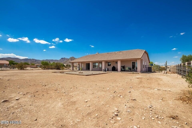 back of property with fence, a mountain view, and stucco siding