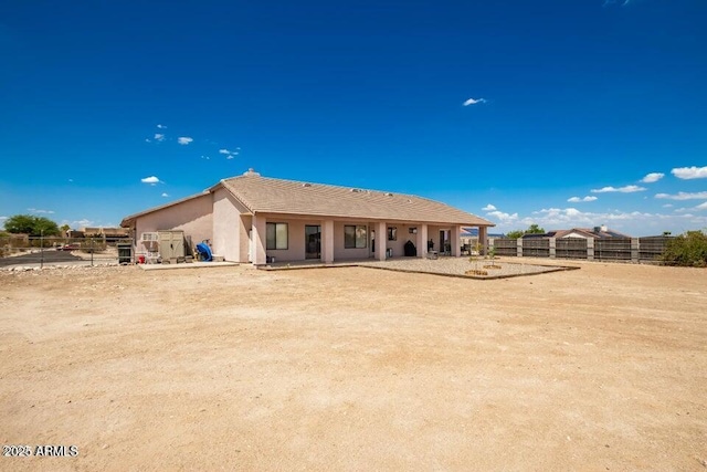 back of property with fence, stucco siding, and a tiled roof