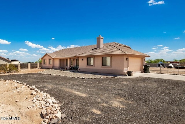 rear view of house featuring fence, an attached garage, driveway, and a tiled roof