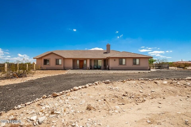 ranch-style house featuring fence, a chimney, and stucco siding