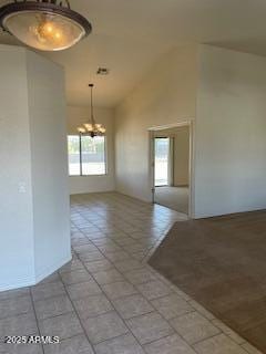 unfurnished room with light tile patterned floors, high vaulted ceiling, a notable chandelier, and a healthy amount of sunlight