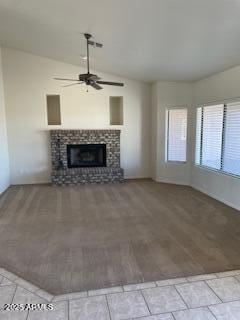unfurnished living room with a ceiling fan, a fireplace with raised hearth, lofted ceiling, and light wood-type flooring