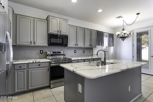 kitchen featuring light tile patterned flooring, pendant lighting, gray cabinetry, a kitchen island with sink, and stainless steel appliances