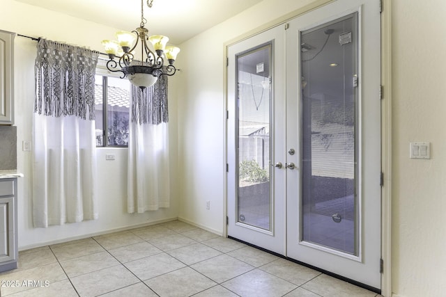 unfurnished dining area with light tile patterned floors, a notable chandelier, and french doors