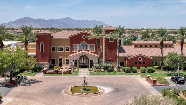 mediterranean / spanish-style house featuring a mountain view, a tiled roof, french doors, stucco siding, and curved driveway