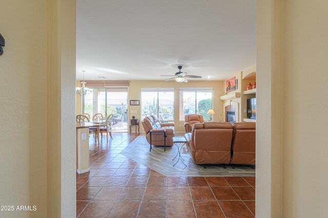 tiled living room with ceiling fan with notable chandelier