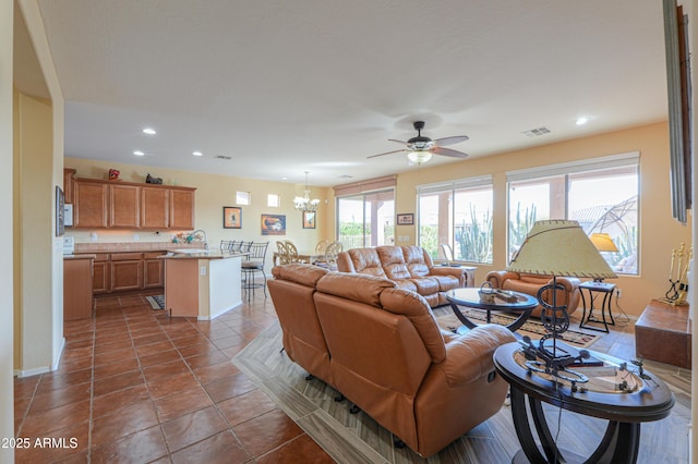 living room featuring dark tile patterned floors and ceiling fan with notable chandelier