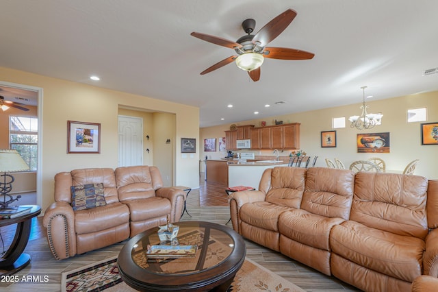 living room featuring ceiling fan with notable chandelier