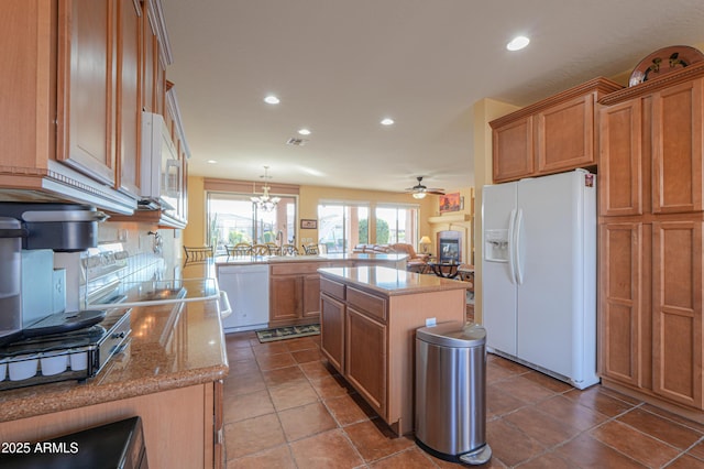 kitchen featuring a center island, kitchen peninsula, pendant lighting, white appliances, and ceiling fan with notable chandelier