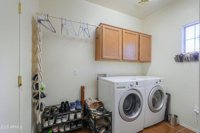 clothes washing area with tile patterned floors, washing machine and dryer, and cabinets