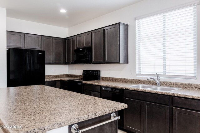 kitchen featuring dark brown cabinetry, sink, a healthy amount of sunlight, and black appliances