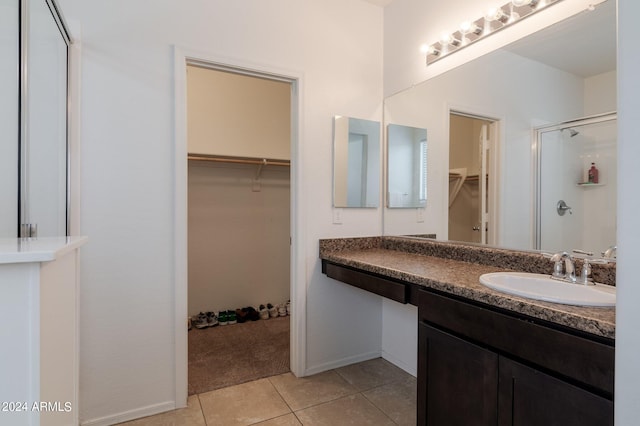 bathroom with a shower with door, tile flooring, and vanity