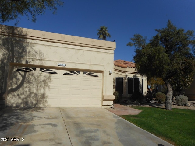 view of front of house featuring a garage, driveway, a tile roof, and stucco siding