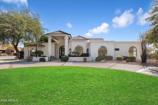 exterior space with driveway, a tiled roof, a front lawn, and stucco siding