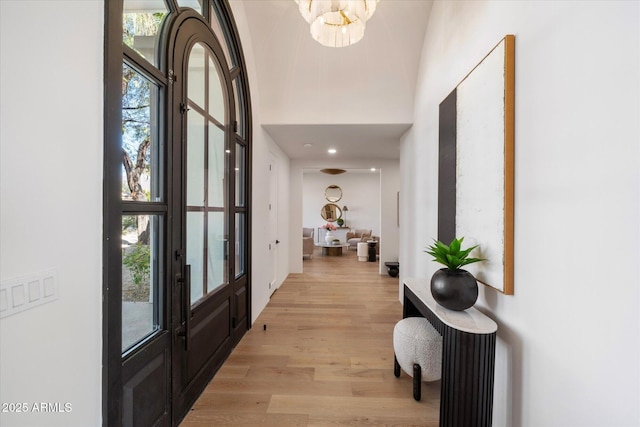 foyer entrance featuring light wood-style floors, a high ceiling, and a chandelier