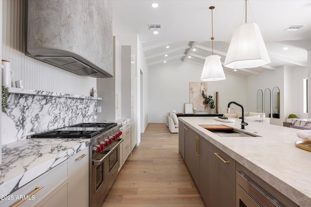 10541 E Windrose Dr, Scottsdale, AZ 85259 - kitchen featuring range with two ovens, vaulted ceiling with beams, hanging light fixtures, light wood-style floors, and a sink