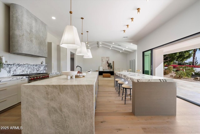 10541 E Windrose Dr, Scottsdale, AZ 85259 - kitchen with light wood-style flooring, a breakfast bar, a spacious island, vaulted ceiling, and decorative light fixtures