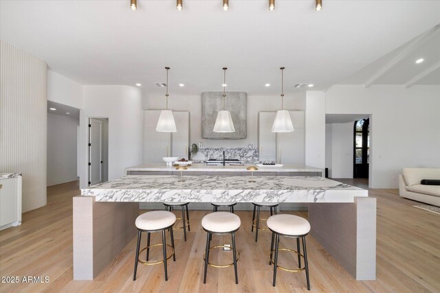 10541 E Windrose Dr, Scottsdale, AZ 85259 - kitchen featuring light wood finished floors, a large island, a breakfast bar, and decorative light fixtures