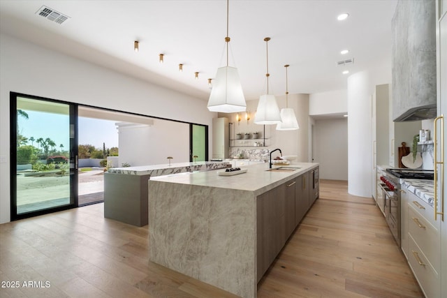10541 E Windrose Dr, Scottsdale, AZ 85259 - kitchen with decorative light fixtures, a sink, visible vents, light wood finished floors, and a large island with sink