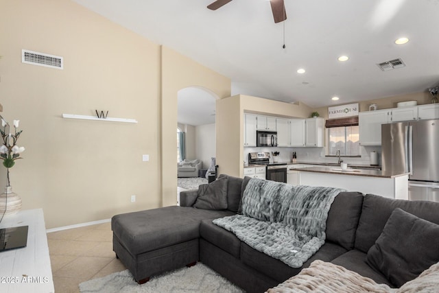 living room featuring arched walkways, ceiling fan, light tile patterned flooring, and visible vents