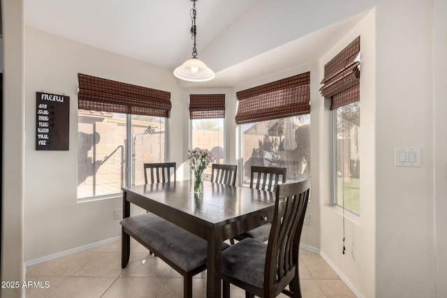 dining area featuring lofted ceiling, light tile patterned flooring, and baseboards