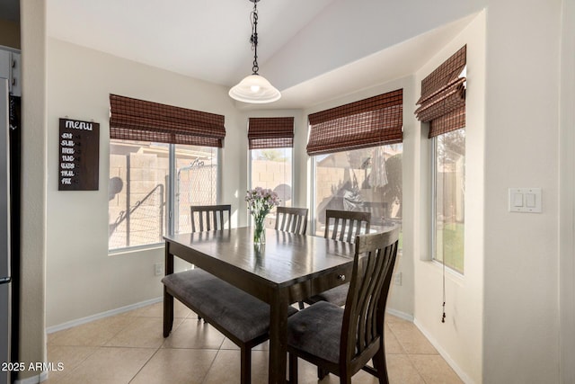 dining space with vaulted ceiling, light tile patterned floors, and baseboards