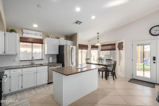 kitchen featuring light tile patterned floors, lofted ceiling, stainless steel appliances, a sink, and visible vents