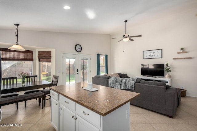 kitchen with light tile patterned floors, a kitchen island, white cabinets, french doors, and decorative light fixtures