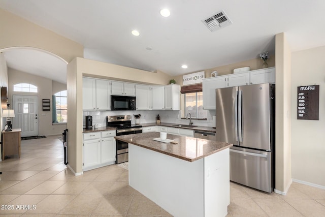 kitchen with arched walkways, stainless steel appliances, a sink, visible vents, and vaulted ceiling