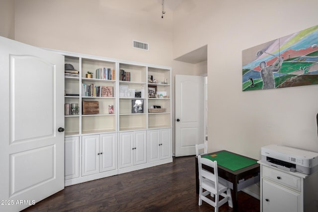 interior space featuring a towering ceiling, dark wood finished floors, and visible vents