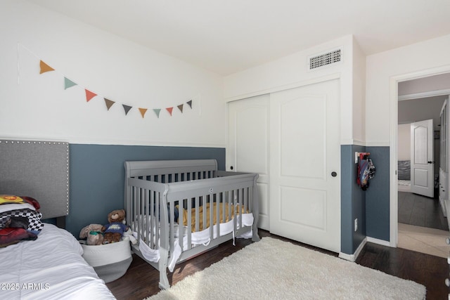 bedroom featuring a closet, visible vents, and wood finished floors