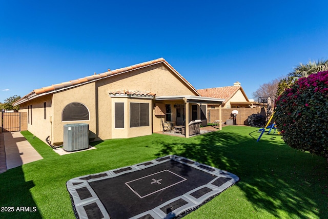 rear view of property featuring a patio area, a fenced backyard, central AC, and stucco siding